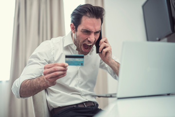 Handsome businessman are furious with credit card and mobile.