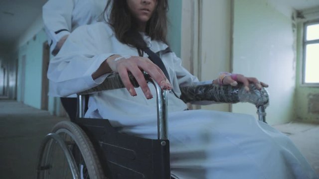 Female Nurse Pushing Patient In The Wheelchair Through The Hospital Corridor