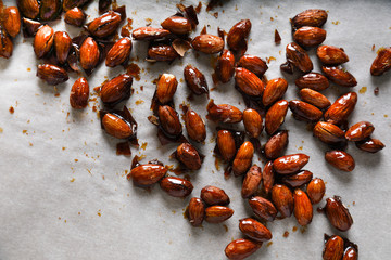 Glazed almonds on parchment on a beige background in a modern style.