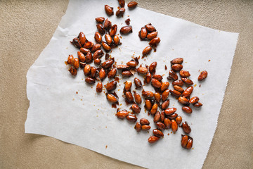 Glazed almonds on parchment on a beige background in a modern style.