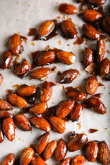 Glazed almonds on parchment on a beige background in a modern style.