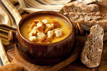 Pea soup with croutons on wooden table