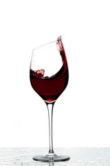 Close up view of splashing red wine in glass isolated on white background. 