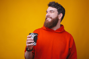 Take your coffee to go. Photo of bearded guy is holding a paper to go coffee cup on yellow background.