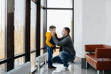 Fototapeta premium A father with his child stands in a mask during the quarantine. Pandemic, coronavirus