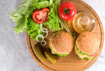  two burgers on a wooden board on a gray background.