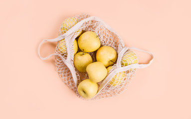 Ripe apples of different varieties in an eco bag on a light background.