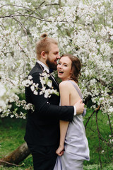 young beautiful couple in the garden against the background of cherry blossoms