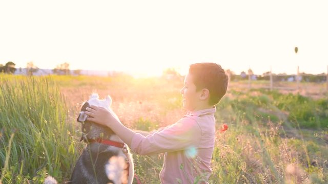Husky dog licked handsome brunette boy in a field out town at sunset