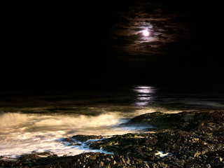 Moon and rainbow clouds reflected in the sea.