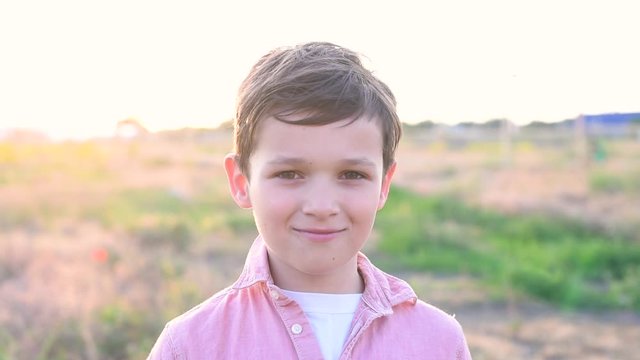 Handsom brunette boy stays and smiling in field