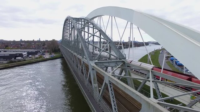 Cinematic aerial drone shot of a industrial cargo train driving over a bridge into a city revealing the skyline 4K