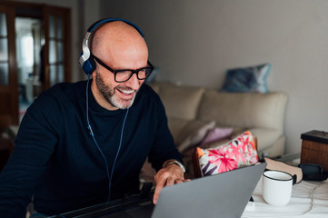 Man working from home on a laptop computer sitting at a desk surfing the internet