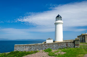 White lighthouse tower and stone fence. Davaar island, Scotland