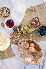 Flat lay Picnic for summer holidays with fresh fruits and berries, laid out on a rug made of straw. 