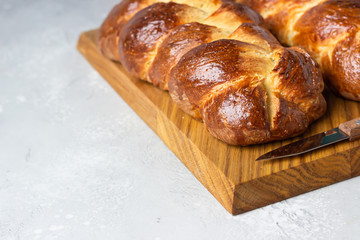 Homemade challah bread or cozonac on a wooden board, light grey stone background. Shabbat, Jewish traditional bread. Easter bakery. 