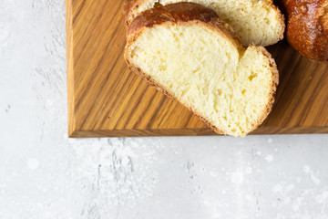 Challah bread or cozonac on a wooden board, light grey stone background. Shabbat, Jewish traditional bread. Easter bakery. Top view.