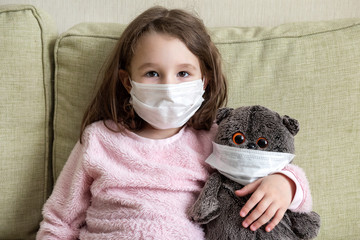 Funny kid with mask during COVID-19 coronavirus pandemic. Stay at home in quarantine. Little girl...