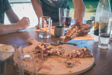 Man taking a delicious fresh home made pizza on a round wooden board in his hands. Outdoor pizza party fresh out of a vintage fireplace.