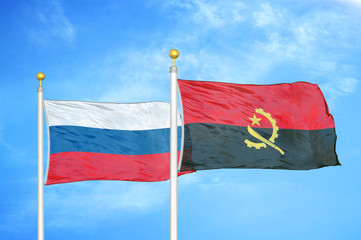 Russia and Angola  two flags on flagpoles and blue cloudy sky