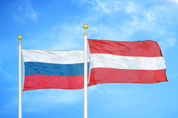 Russia and Austria  two flags on flagpoles and blue cloudy sky