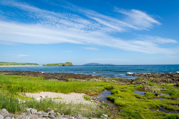 Kintyre peninsula shores, green grass and blue sky at nice summer day in Scotland