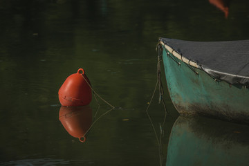 Detail of an old green boat moored at a plastic buoy on a lake of Most na Soci on Soca river.