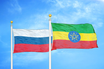 Russia and Ethiopia two flags on flagpoles and blue cloudy sky