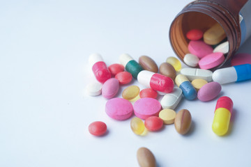 color pills spilling from container on isolated on white 