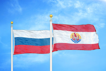 Russia and French Polynesia two flags on flagpoles and blue cloudy sky