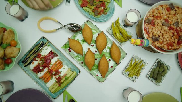 Top view of Turkish family dinner table, hands serving kibbeh