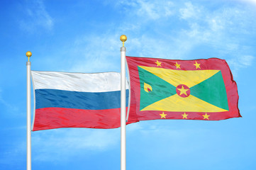 Russia and Grenada two flags on flagpoles and blue cloudy sky