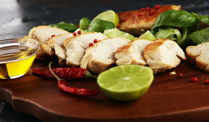 Partially sliced grilled chicken breast on cutting board on table