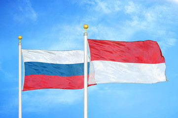 Russia and Indonesia two flags on flagpoles and blue cloudy sky
