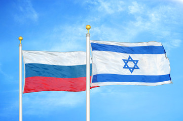 Russia and Israel two flags on flagpoles and blue cloudy sky