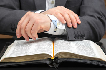 male hands lie on an open holy bible close up. the search for God and the study of the book