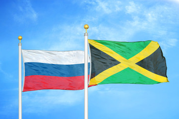 Russia and Jamaica two flags on flagpoles and blue cloudy sky