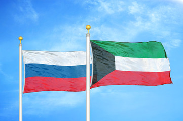 Russia and Kuwait two flags on flagpoles and blue cloudy sky