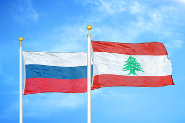 Russia and Lebanon two flags on flagpoles and blue cloudy sky