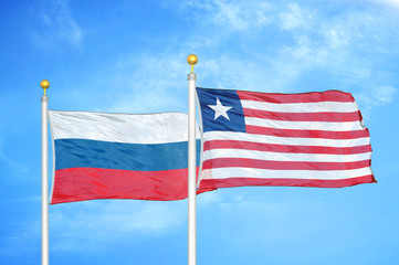 Russia and Liberia two flags on flagpoles and blue cloudy sky