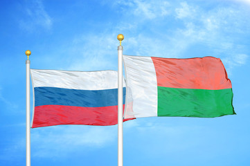 Russia and Madagascar two flags on flagpoles and blue cloudy sky
