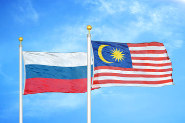 Russia and Malaysia two flags on flagpoles and blue cloudy sky