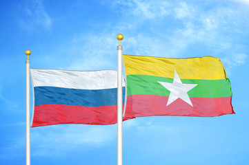Russia and Myanmar two flags on flagpoles and blue cloudy sky