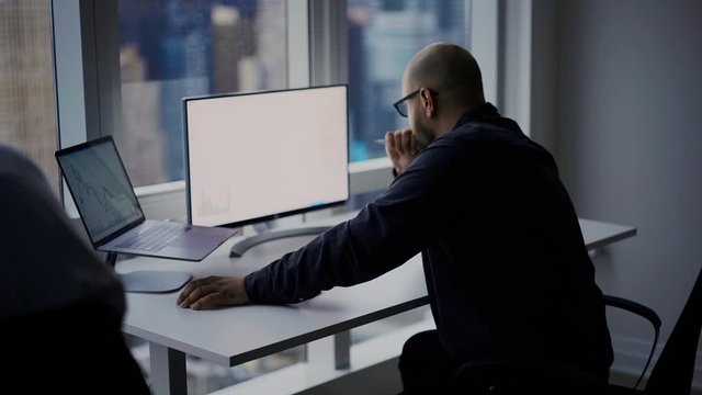 Businessman sitting at office desktop with modern digital technology for checking deposit balance, blank monitor of PC computer with copy space area for financial advertising

