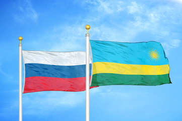 Russia and Rwanda two flags on flagpoles and blue cloudy sky