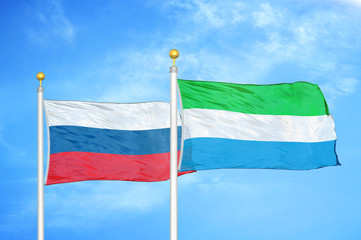 Russia and Sierra Leone two flags on flagpoles and blue cloudy sky