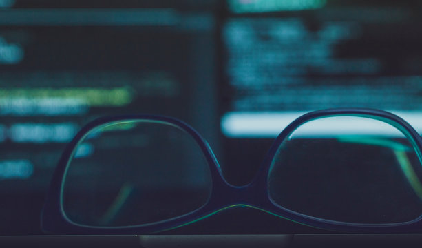 glasses and screen with code in background 