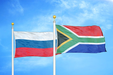 Russia and South Africa two flags on flagpoles and blue cloudy sky