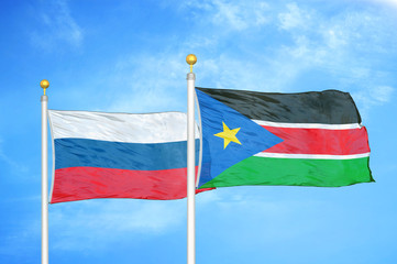 Russia and South Sudan two flags on flagpoles and blue cloudy sky