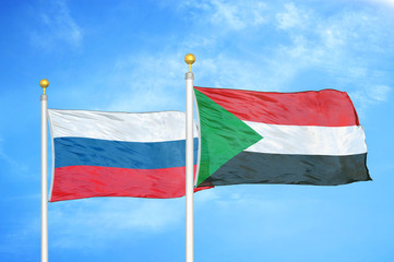 Russia and Sudan two flags on flagpoles and blue cloudy sky